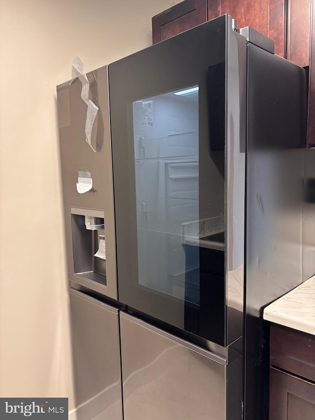 room details with dark brown cabinets, stainless steel fridge, and light countertops