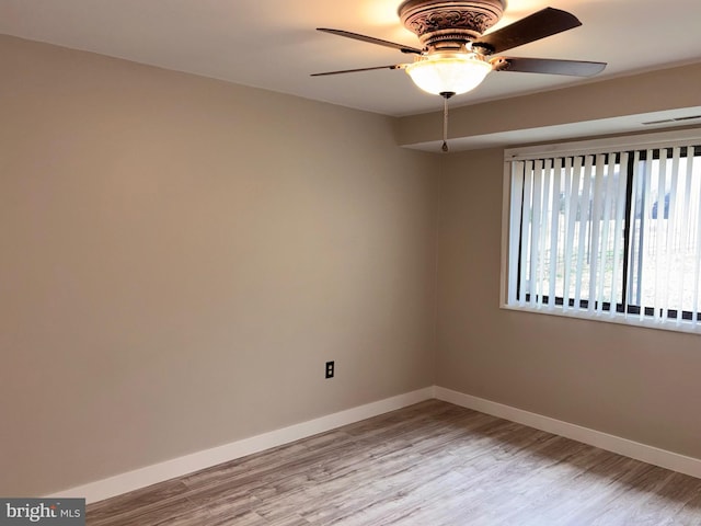 unfurnished room featuring light wood-type flooring, baseboards, and a ceiling fan