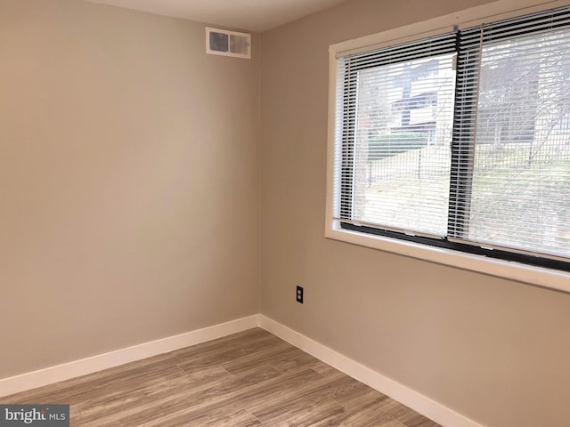 spare room featuring visible vents, light wood-style flooring, and baseboards