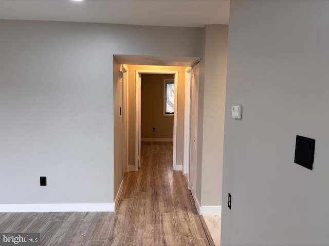 hallway featuring light wood-type flooring and baseboards