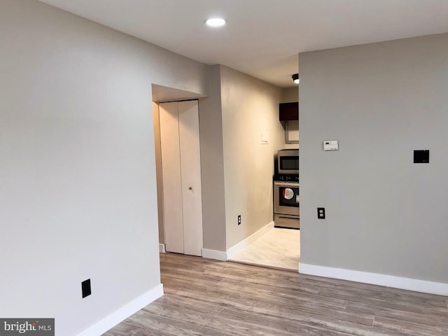 spare room with recessed lighting, baseboards, and light wood finished floors