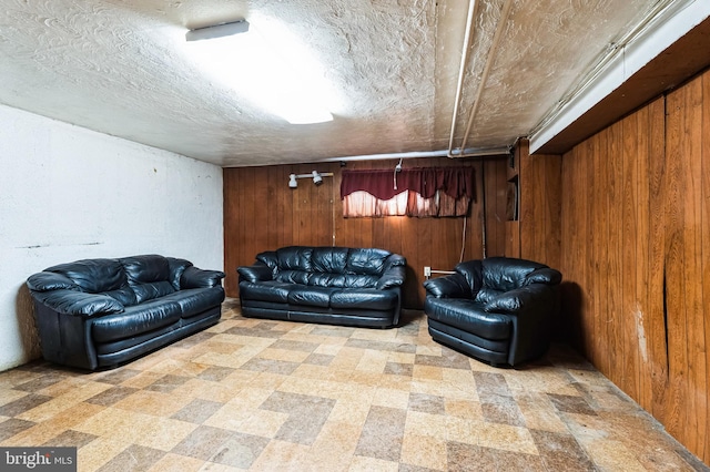 living area featuring tile patterned floors, wood walls, and a textured ceiling