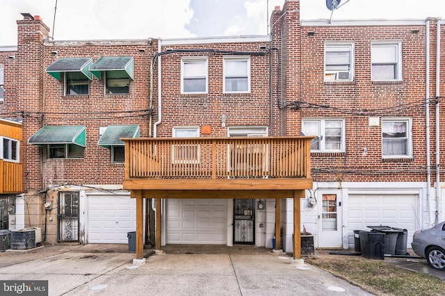 back of house with brick siding, cooling unit, driveway, and a garage