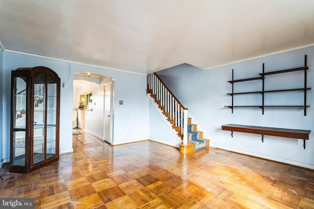 empty room with baseboards, arched walkways, ornamental molding, and stairs