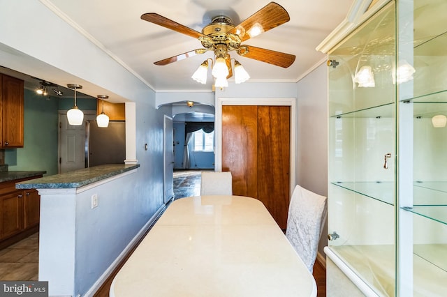 dining space featuring crown molding, arched walkways, and ceiling fan