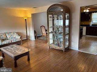 living room with baseboard heating, wood finished floors, and a ceiling fan