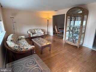 living area featuring wood finished floors, arched walkways, and baseboards