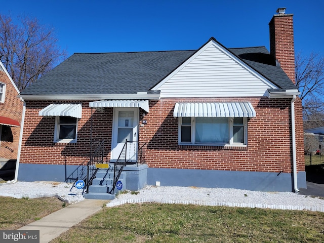 bungalow-style home with a shingled roof, brick siding, and a chimney