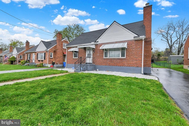 bungalow-style home with a residential view, brick siding, a chimney, and a front lawn