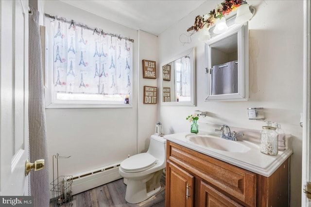 bathroom featuring a baseboard heating unit, wood finished floors, toilet, and vanity