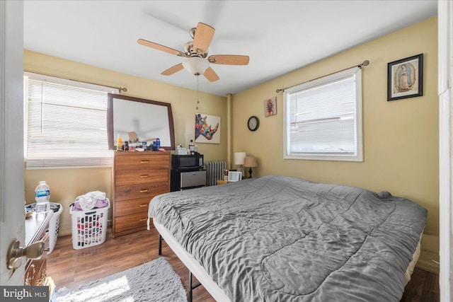 bedroom featuring radiator, wood finished floors, and a ceiling fan