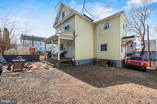 rear view of house with covered porch and fence