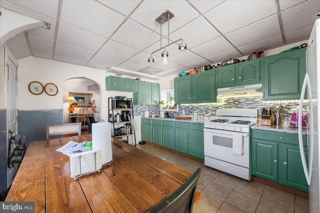 kitchen featuring white appliances, arched walkways, a paneled ceiling, under cabinet range hood, and tasteful backsplash