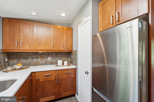 7711 Holmes Run Dr, Falls Church, VA 22042 - kitchen with dark tile patterned floors, freestanding refrigerator, brown cabinets, and tasteful backsplash