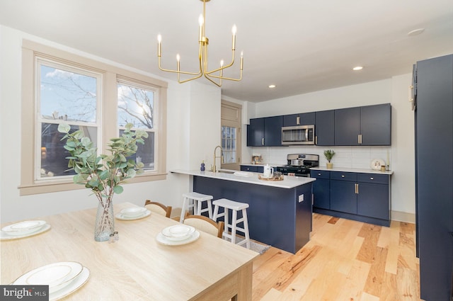 kitchen featuring backsplash, light countertops, light wood-style floors, stainless steel appliances, and a sink