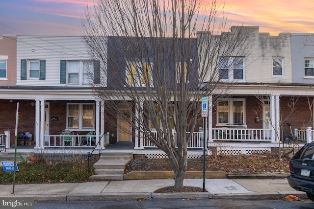 view of property featuring brick siding and covered porch