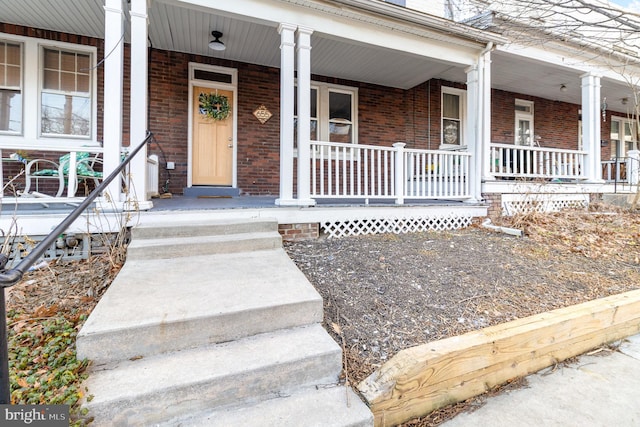 doorway to property with brick siding and covered porch