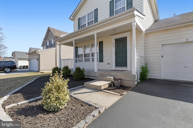 view of exterior entry featuring an attached garage and covered porch