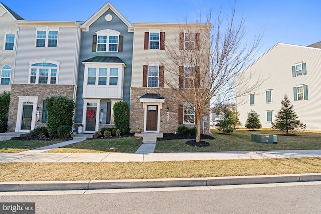 townhome / multi-family property featuring a front lawn