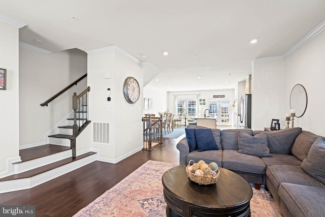 living area featuring dark wood-type flooring, crown molding, visible vents, and baseboards