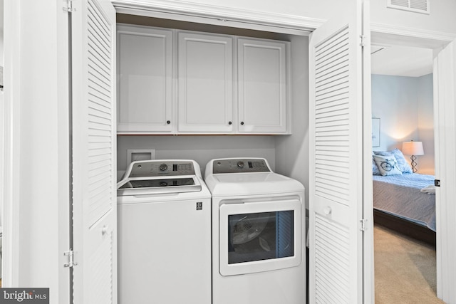 clothes washing area featuring carpet flooring, cabinet space, visible vents, and washing machine and clothes dryer