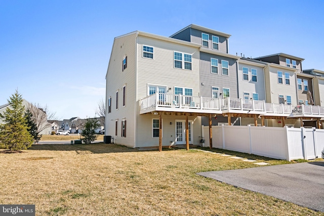 rear view of house with central air condition unit, a lawn, a residential view, and fence