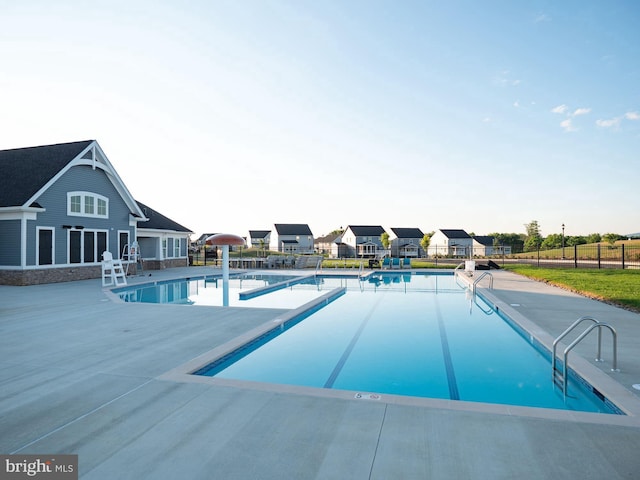 community pool featuring a patio area, a residential view, and fence