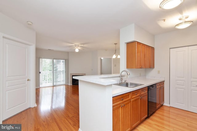 kitchen featuring a fireplace, a sink, light countertops, black dishwasher, and light wood-style floors