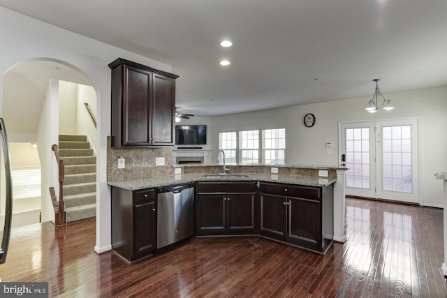 kitchen with dark wood finished floors, a peninsula, stainless steel dishwasher, a ceiling fan, and a sink