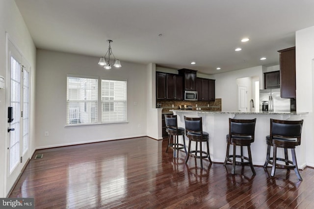 kitchen featuring light stone counters, visible vents, dark wood-style flooring, decorative backsplash, and appliances with stainless steel finishes