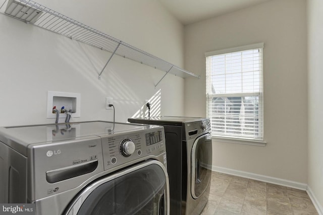 laundry area with laundry area, washing machine and dryer, and baseboards