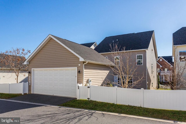 view of front facade with aphalt driveway, a garage, and fence