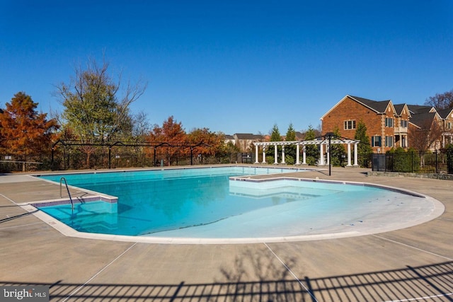 community pool with a pergola, a patio, and fence