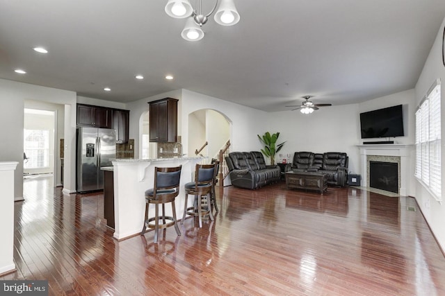 kitchen featuring hardwood / wood-style floors, light stone countertops, plenty of natural light, dark brown cabinetry, and stainless steel fridge