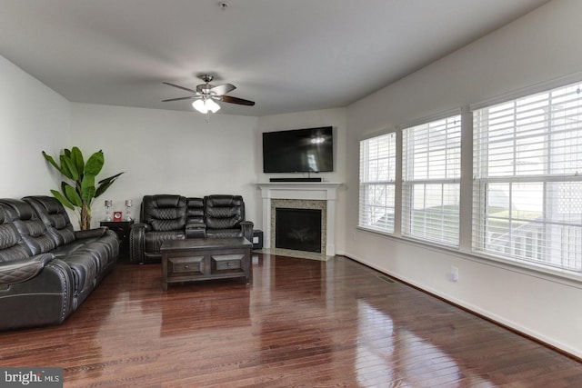 living room featuring wood finished floors, baseboards, visible vents, a fireplace with flush hearth, and ceiling fan