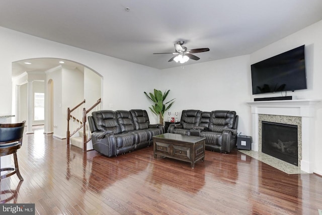 living room with ceiling fan, a fireplace with flush hearth, recessed lighting, wood finished floors, and arched walkways