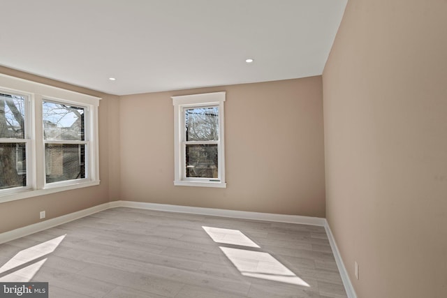 spare room featuring recessed lighting, baseboards, and light wood finished floors