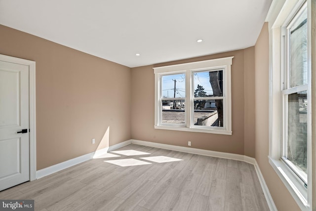 empty room featuring recessed lighting, baseboards, and light wood-style floors