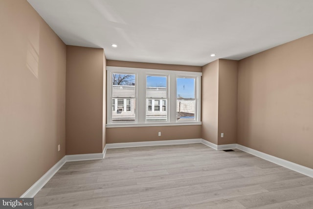 empty room featuring recessed lighting, light wood-style flooring, and baseboards