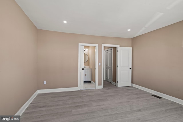 unfurnished bedroom featuring recessed lighting, baseboards, light wood-style floors, and ensuite bath