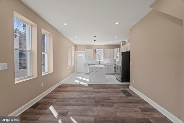 unfurnished living room with dark wood-type flooring, recessed lighting, baseboards, and visible vents