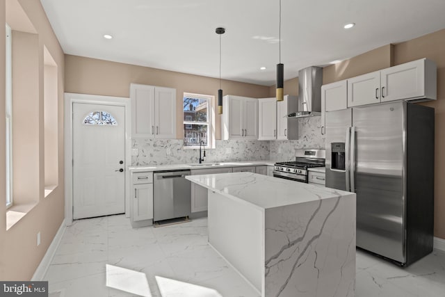 kitchen with a sink, marble finish floor, appliances with stainless steel finishes, wall chimney exhaust hood, and tasteful backsplash