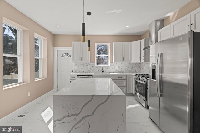 kitchen with backsplash, appliances with stainless steel finishes, marble finish floor, wall chimney exhaust hood, and a sink