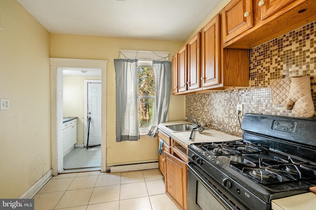 1121 E 22nd St, Wilmington, DE 19802 - kitchen featuring backsplash, brown cabinets, a sink, black gas range oven, and light tile patterned flooring