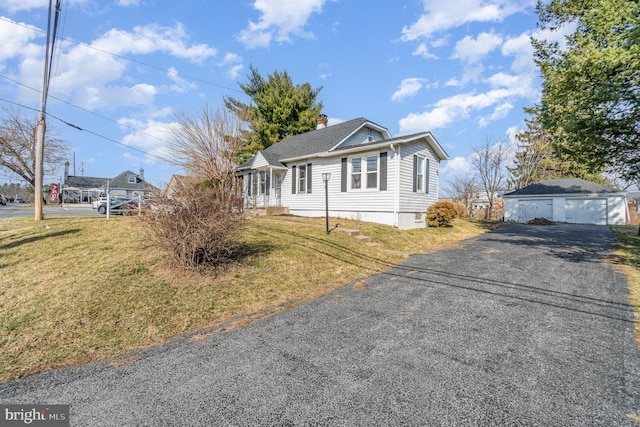 bungalow-style house with a chimney, a front lawn, an outdoor structure, and a garage