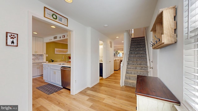 hall with a sink, light wood-style floors, recessed lighting, and stairs