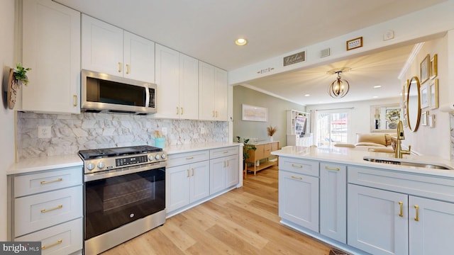 kitchen featuring light wood finished floors, light countertops, decorative backsplash, recessed lighting, and appliances with stainless steel finishes