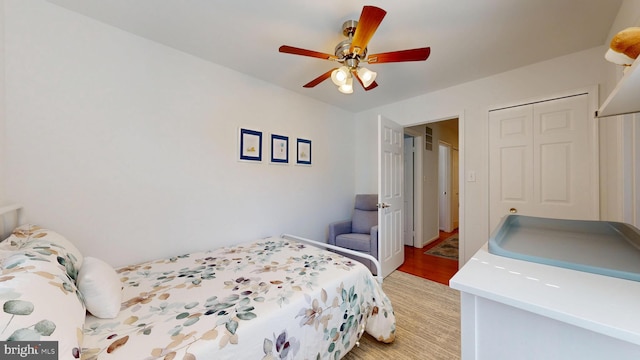 bedroom with a ceiling fan, light wood-style floors, and a closet