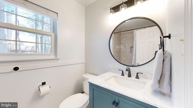 bathroom featuring toilet, vanity, and a shower with curtain