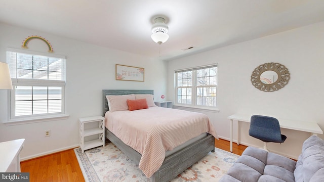 bedroom with visible vents, baseboards, and wood finished floors